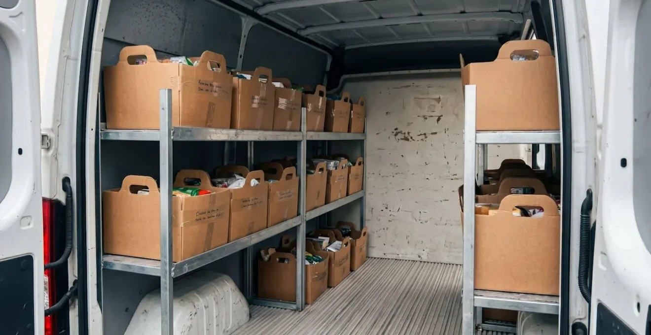 Intérieur utilitaire de livraison avec corbeilles carton empilées sur étagère métallique, légère condensation visible sur parois