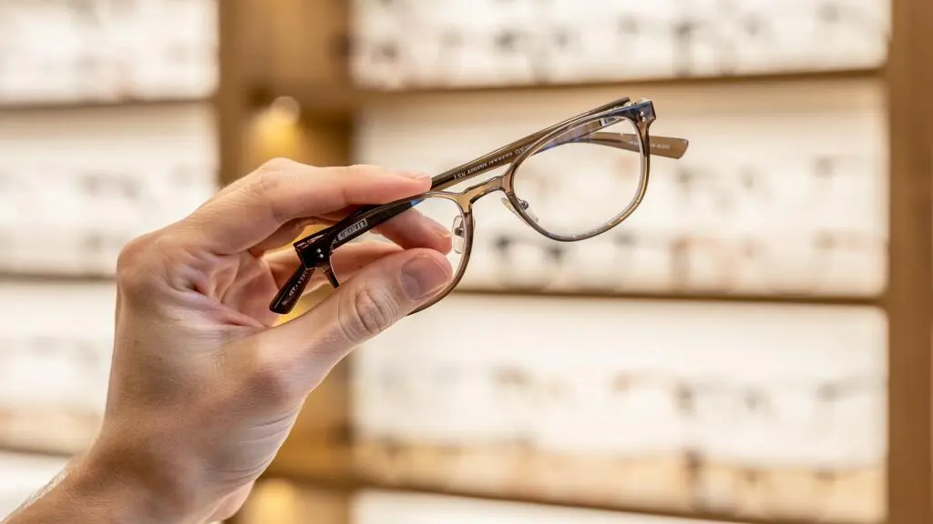 Un opticien compare deux montures plastique en montrant les plaquettes de nez.